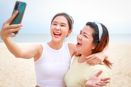 Two fat and slim Asian girls having fun enjoying sea travel holding smartphones taking selfies. Travel woman. Travel and lifestyle conceptの写真素材
