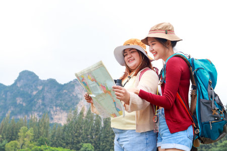 Portrait of two Asian female travelers carrying backpacks Standing looking at map to travel nature....