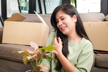 Portrait of an Asian woman doing a business selling plants online. Talking on the phone and packing products into paper boxes to send to customers. Entrepreneurship Concept, Small Business, SMEの写真素材