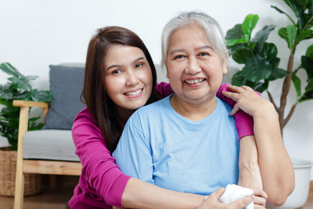 Portrait of a daughter with an elderly Asian mother smiling happily. Sit and cuddle in the living...