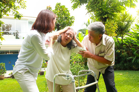Family concept. Daughter and father taking care of elderly mother Suffering from Alzheimer's disease, living at home. elderly health care. headache elderlyの写真素材