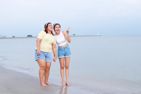 Two fat and thin Asian girls travel the sea on vacation. Stand and watch the sea on the beach. Travel woman. Travel and lifestyle concept. copy spaceの写真素材
