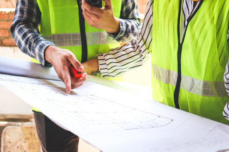 Engineer and Architect or Foreman Holding a walkie talkie and a blueprint on a construction site. Architecture concept, building constructionの写真素材