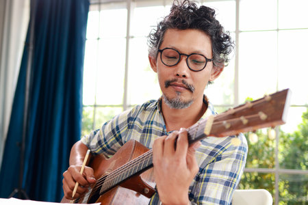 Asian male musicians sitting guitar instrument Acoustic and currently composing music. music conceptの写真素材