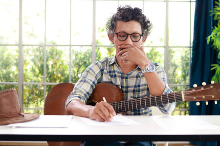 Asian male musicians sitting guitar instrument Acoustic and currently composing music. music conceptの写真素材