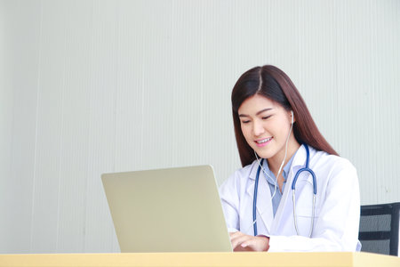 Beautiful Asian female doctor using a laptop computer working in the office. Online doctor concept. copy spaceの写真素材