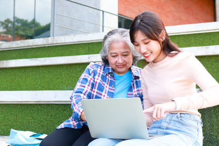 Asian university students of different ages use laptops to study and prepare for exams or work on...