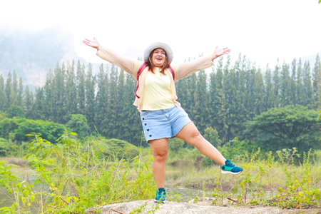 Fat female Asian tourist standing with arms and legs spread. fun happy Among the natural forests and high mountains. Travel concept, trekkersの写真素材