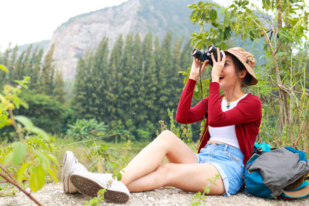 Asian female tourist enjoying nature tourism using binoculars for bird watching. adventure life travel concept, traveler, trekking. copy spaceの写真素材