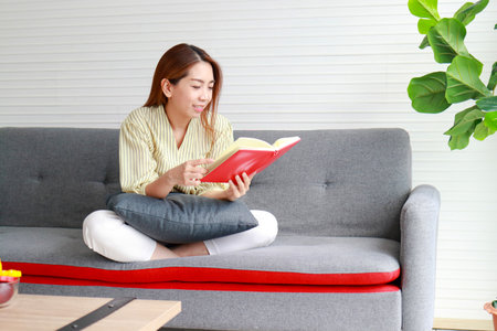 Asian woman relaxing at home on weekends Sit on the sofa and read a book. health care conceptの写真素材