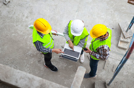 Top view of group of engineers, architects and contractors standing and discussing in building...