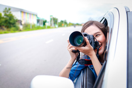 Beautiful Asian woman traveling in private car holding camera. Transport concept, tourism. Asian...