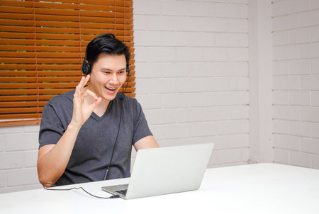 Asian men Use a laptop computer and wear headphones. Sit and work at your desk at home. Business concept. modern communication. copy spaceの写真素材