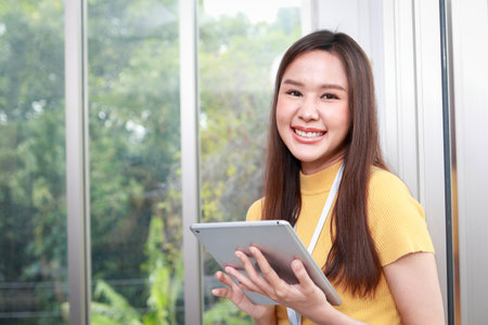 Young asian woman working in office smiling happy holding tablet for online work. business woman office worker. copy spaceの写真素材