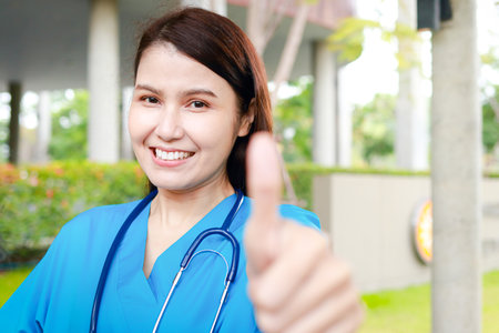 Asian female doctor wearing blue surgical gown Beautiful smile, thumbs up. concept of medical services in a hospitalの写真素材