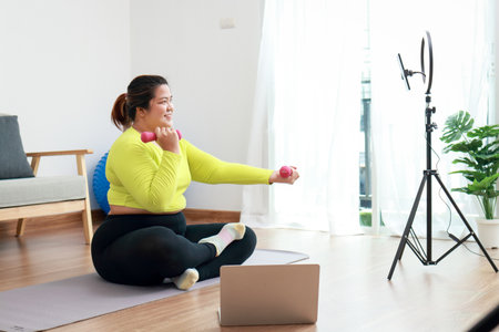 Fat woman blogger athlete in sportswear exercise in the room Publish content online on social media platforms. sports concept Exercise and healthy health care.の写真素材