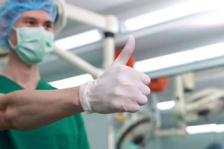 A professional surgeon working in the thumbs up operating room is pleased with his work. medical...