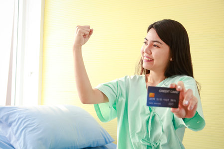 Beautiful Asian patient holding a credit card to pay medical bills. concept of health insuranceの写真素材
