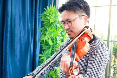 Asian male musicians enjoy playing the violin. Classical stringed instruments. Bands and live music performances. classical music teacherの写真素材