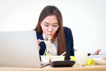 Portrait of a beautiful girl, an employee or an executive in an office wearing a blue suit, eating at a desk. business conceptの写真素材