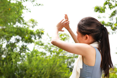Asian woman exercising outdoors on a hot sunny day, body temperature above 40 degrees Celsius, using her hands to cover the sun. heat strokeの写真素材