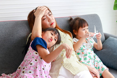 Single mother working at home Tired, busy with work and having to take care of two daughters who are playing mischievously. Family concept. working woman head of familyの写真素材