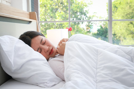 Asian woman lying sick in bed in bedroom She has a headache. flu, viral infectionの写真素材