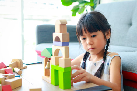 Asian little girl with pigtails Sitting on the sofa in the house with wooden toys. Education concept, child development learningの写真素材
