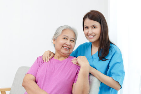 Physiotherapist with elderly female patient sitting on sofa in treatment room. Doctors and seniors. Physical therapy in the health centerの写真素材