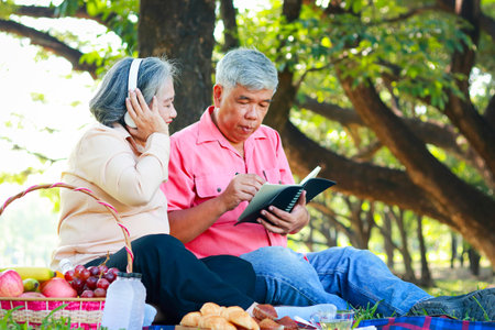 Happy Asian elderly couple Picnic sitting in the park. Living in retirement to be happy. Elderly health careの写真素材