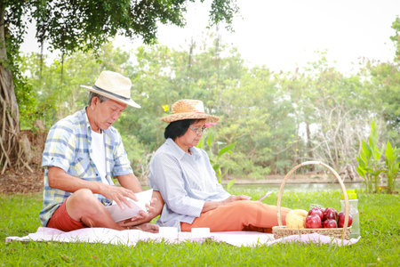 Happy Asian elderly couple Picnic sitting in the park. Living in retirement to be happy. Elderly health careの写真素材