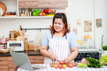 Asian woman learns to cook online By looking at the process of doing it through a laptop. Housewife cooking. weight loss dietの写真素材