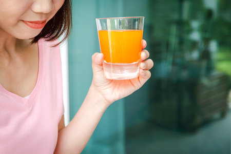 Asian woman holding a glass of freshly squeezed orange juice. Healthy food concept.の写真素材
