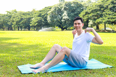Asian man exercising outdoors in the garden sitting on a yoga mat. exercise for health. copy spaceの写真素材