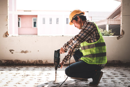 Asian construction worker using mortar extraction machine to drill concrete floor. Industry concept,...