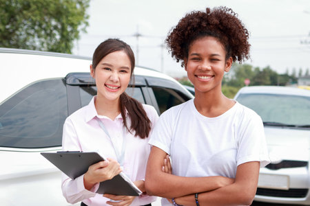 Insurance business concept. A pretty young insurance agent holds claim documents for a customer whose car was damaged in a road accident.の写真素材