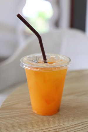 A glass of orange juice is placed on a wooden table in a cafe. Fruit drink concept.の写真素材