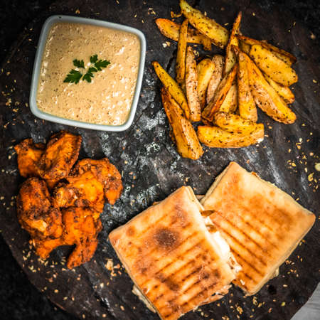 Pepperoni paninos, rustic potatoes and spicy fried chicken with house sauce.の写真素材