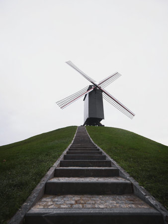 Panorama of trail path to historic traditional Bonne Chieremolen windmill post mill in Bruges West Flanders Belgiumの写真素材