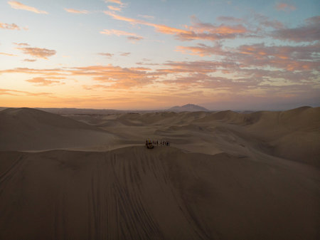 Aerial postcard panorama sunset view of buggy tour grop on dry sand dunes desert of Huacachina Ica Peru South Americaの写真素材
