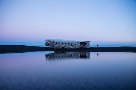 Panorama pond lake reflection of Solheimasandur DC3 airplane wreck crash site on black rock volcanic ashes beach Icelandの写真素材