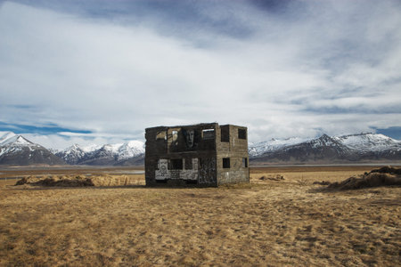 Abandoned forgotten lost place building house farm shed grass landscape in front of mountain range in Vidbord Icelandの写真素材