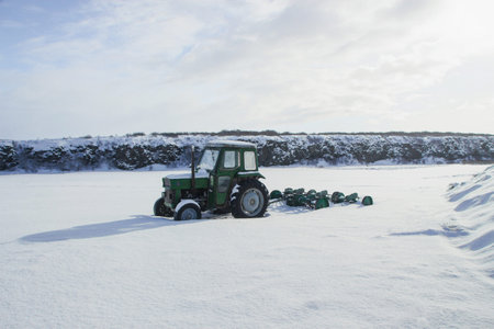 Green old tractor farm machine vehicle stuck in snow winter panorama nature landscape North Iceland Europeの写真素材