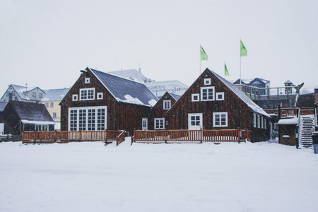 Winter wonderland snow panorama typical traditional wooden house building waterfront in Husavik...