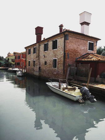 Old rustic mediterranean brick house building with boat on canal of Torcello Island Venetian Lagoon...