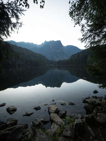 Sunrise panorama mirror reflection view of alpine forest mountain lake Piburger See Oetztal Alps...