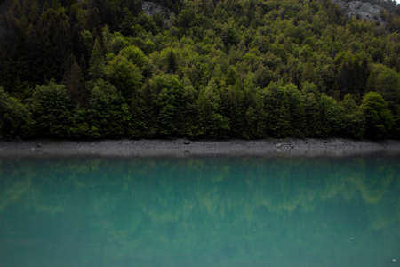 Panorama reflection of turquoise bright blue colored alpine mountain lake reservoir Mapragg...