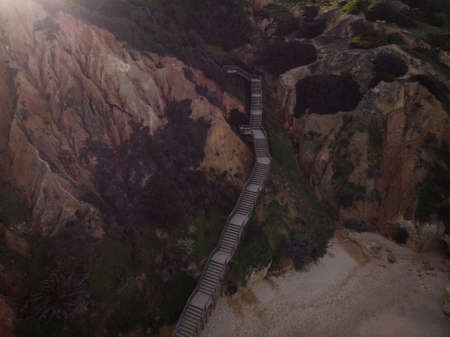Aerial top down panorama of wooden walkway stairs staircase stairway leading down to Praia do Camilo...