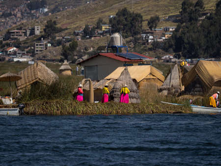 Indigenous women in colorful traditional dresses on Uros Floating reed Islands on Lake Titicaca...