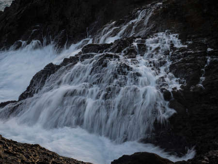 Long exposure close up of rough whitewater ocean wave sea water flowing down cliff rock cascade natural power splash spray force in Galicia Spain Europeの写真素材